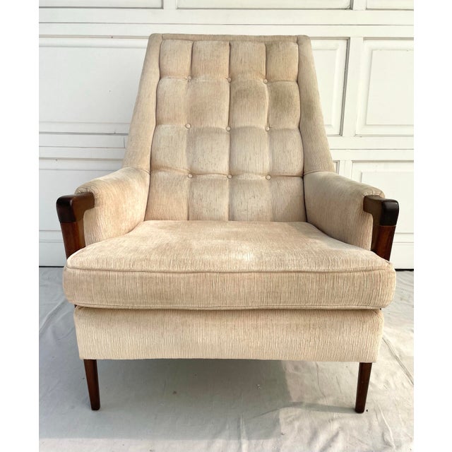 Here is a wonderful, high back lounge chair from the mid-century featuring beautiful wood arms and tufted upholstery. The...