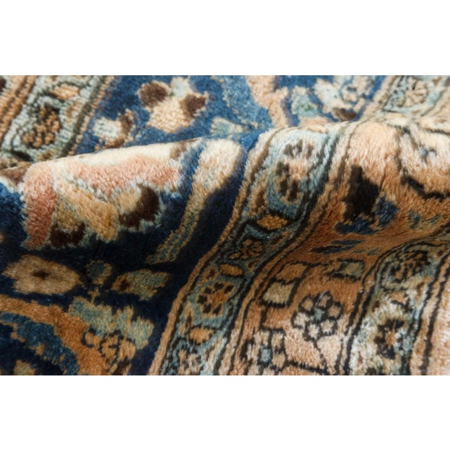 An early 20th century Persian Mashad Persian rug, the caramel ground with a cloudband, flowering vinery and stylized...