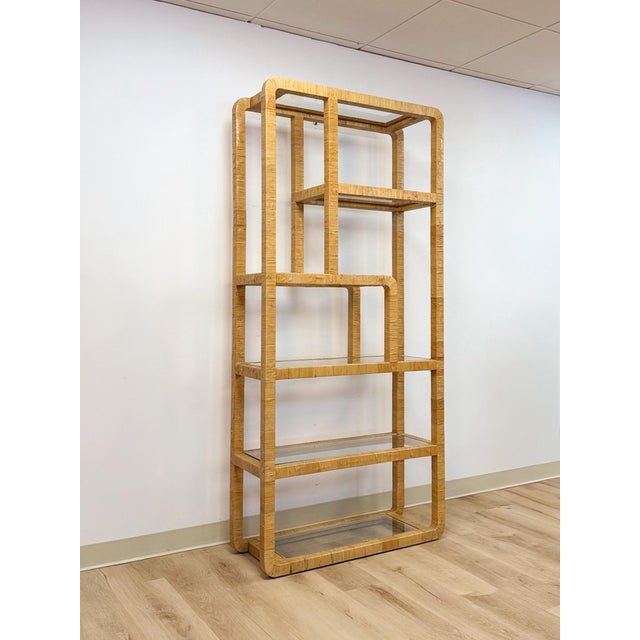 This striking vintage rattan wrapped five-tier etagere with glass shelves in the style of Milo Baughman is a beautifully...