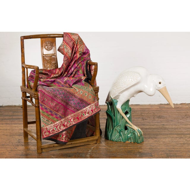 A vintage Chinese ceramic life Size heron bird sculpture from the Mid-20th Century, with green glaze, cream accents and...