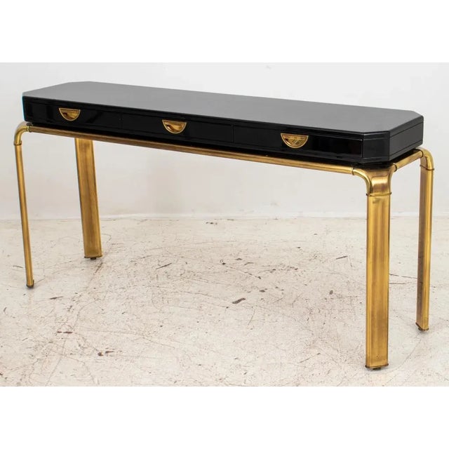 Classic console table designed by John Widdicomb for Mastercraft. Composed of a large black lacquered wood top with canted...