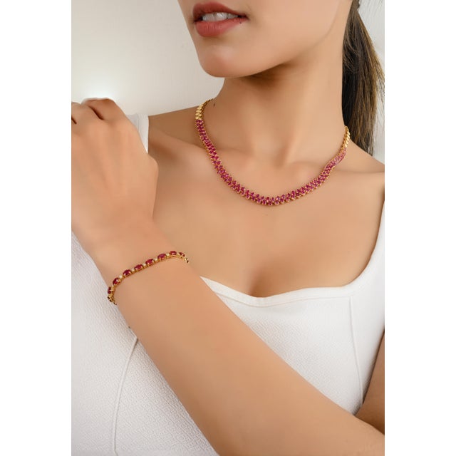 This exquisite choker necklace features a stunning 10.86ctw pear-cut ruby gemstone, radiating a deep, rich red hue....