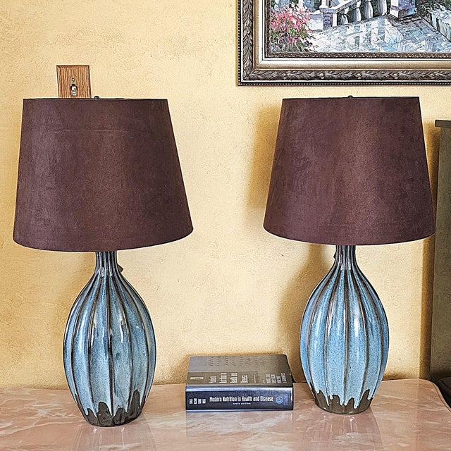 Beautiful pair of turquoise pottery table lamps featuring a glossy ribbed ceramic base with deep blue and teal tones,...