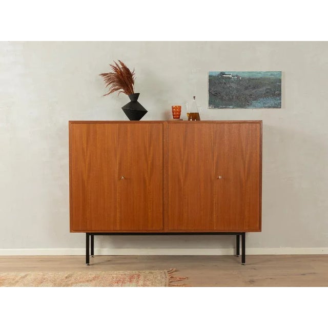 Classic highboard from the 1950s. High quality body in teak veneer with four closet doors, four shelves and new square...