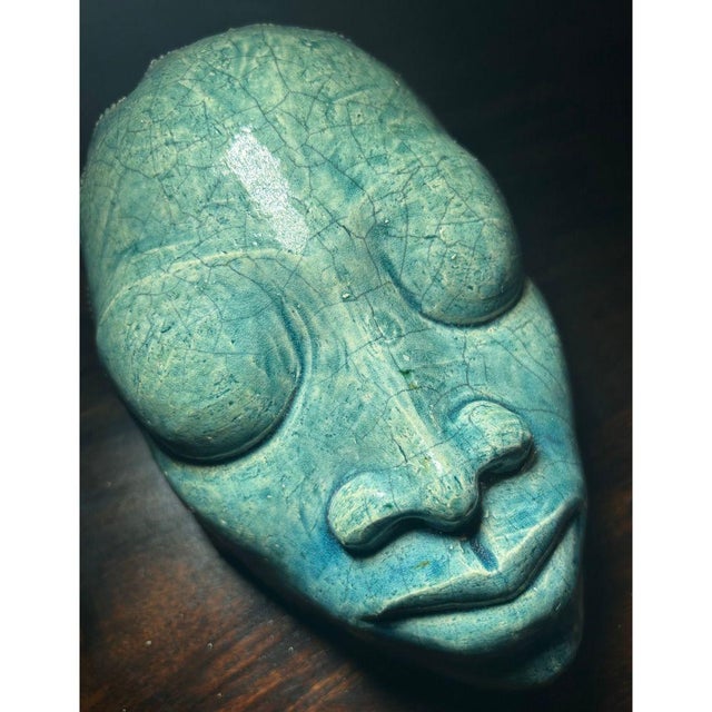 A serene and soulful ceramic mask by celebrated Jamaican artist Gene Pearson, showcasing his signature sculptural elegance...