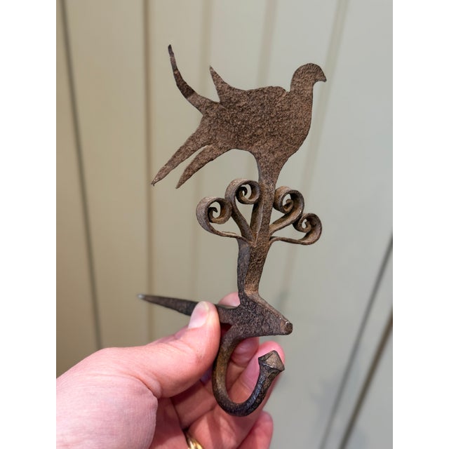 Exceptional early forged iron wall hook featuring a stylized bird finial and beautifully executed hand-forged scrollwork,...