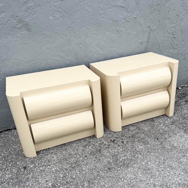 This pair of postmodern nightstands combines a glossy cream laminate finish with bold sculptural curves. Each features two...