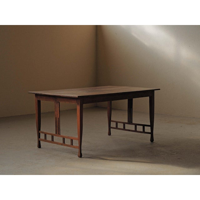 Solid oak table in the Arts and Crafts style, featuring a broad plank top and a sturdy frame with slightly tapered legs....