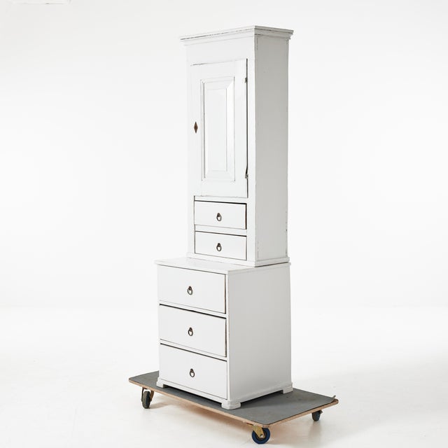A narrow cabinet with two drawers at the bottom and two smaller drawers at the top. There are two shelves behind the...