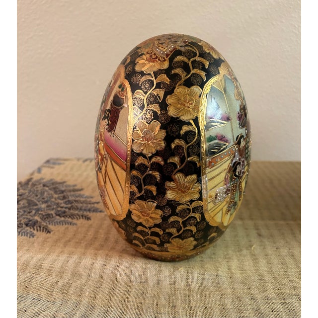 Offering a well sized vintage Cloisonné Satsuma egg featuring palace scenes with geishas and gold gilt lotus blossoms on a...
