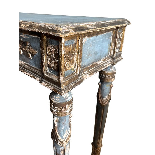This beautiful carved, painted console is from the 20th century. It is a stunning pale blue with a floral relief design...