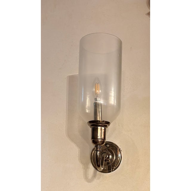 The Ann-Morris Finch Sconce with Hurricane Glass in polished nickel is a premium, handcrafted wall light that brings a...