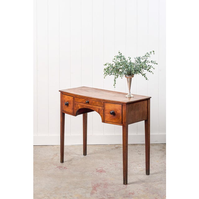 This 19th-century bowfront dressing table features three drawers fitted with wooden knobs and a small contrast border...