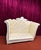 Statement loveseat featuring ivory button-tufted upholstery, an ornate white frame, a decorative crest, and a dramatic...