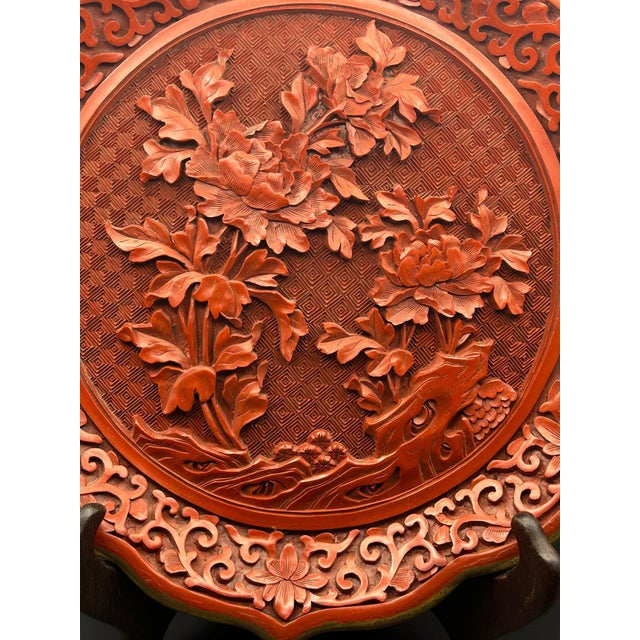 A stunning example of red lacquer Chinese Cinnabar, featuring a high relief center cartouche of chrysanthemums, with...
