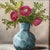 This 10x10 floral still life painting of purple pink Ranunculus Flowers in a gray blue honeycomb hexagon style vase,...