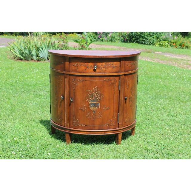 Clean lines and handpainted floral motifs define this diminutive demilune cabinet by Ethan Allen. The three doors open up...