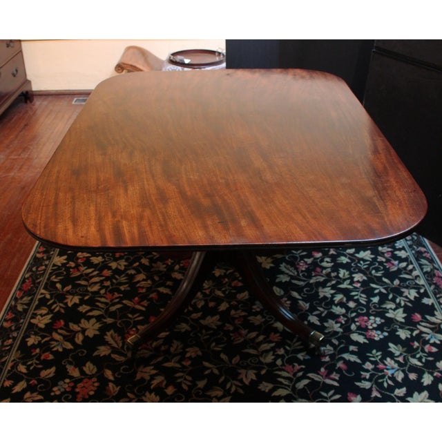 Circa 1825 rectangular tilt-top breakfast or center table, English. Raised on ring turned pedestal with four downswept...