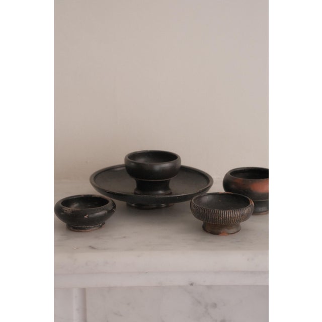 Set of five black-glazed earthenware pieces from Ancient Greece, presumably 4th–3rd century BC. The group comprises a...