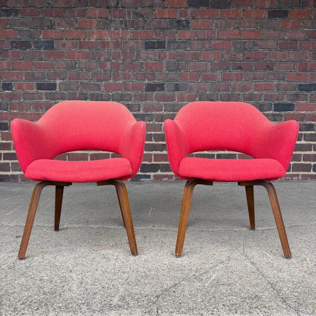 This is a pair of Eero Saarinen for Knoll executive armchairs finished in a red upholstery with walnut legs.