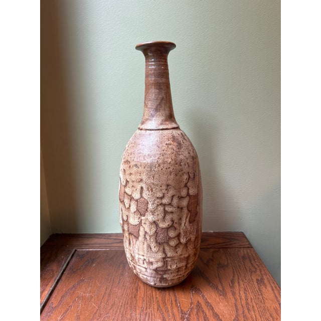 Beautiful handcrafted stoneware vessel with a rich brown glaze and striking crawling ("fat lava") glaze over the body....