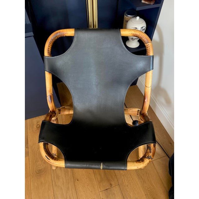 Armchair with back in black leather with shoulder strap and bamboo. 60s. Leather in excellent general condition, with the...