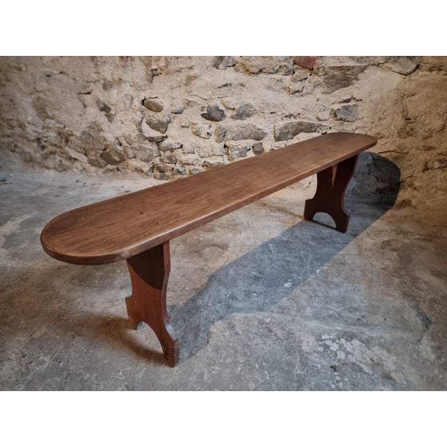 French bench from the 1930s, made of solid cherry wood. The piece features a long, narrow seat with softly rounded ends,...