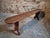 French bench from the 1930s, made of solid cherry wood. The piece features a long, narrow seat with softly rounded ends,...