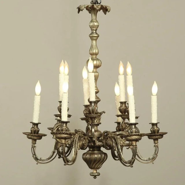 19th Century French Louis XIV Bronze Chandelier with 12 Lights features stunning foliate motifs expressed in a variety of...