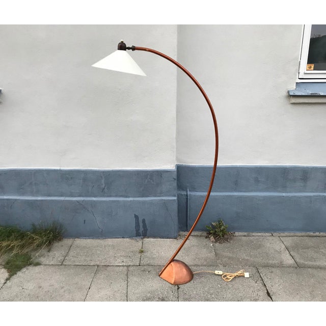 A large arched floor lamp (H: 165 cm). It has a heavy organically shaped cast iron foot and a white adjustable...