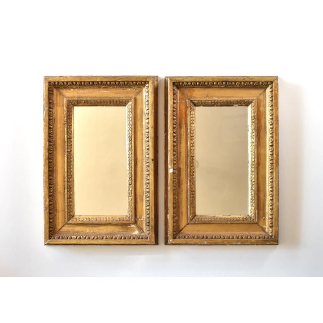 A pair of matching antique, mid-18th-century French gold gilt wood mirrors, in a simple narrow rectangular shape, with a...