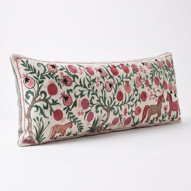 An extra-long lumbar pillow cover made from hand-embroidered Uzbek Suzani cotton — pink pomegranate vines with embroidered...