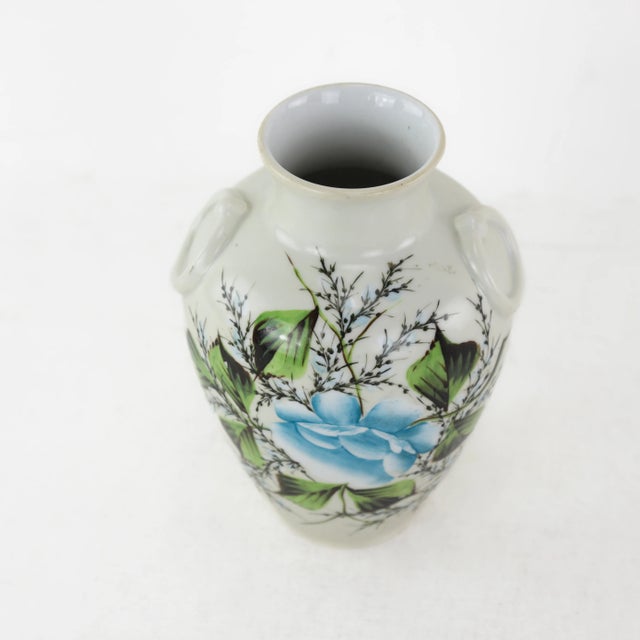Elevate your space with this vintage hand-painted porcelain vase featuring a striking blue floral design surrounded by...