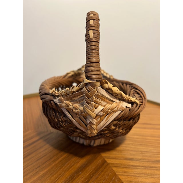 Lovely vintage handwoven buttocks basket featuring an intricate diamond-patterned weave and a tightly wrapped handle. This...