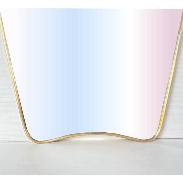 Unique "shield"-shaped mirror from 1970, made entirely of brass with a wooden back and sturdy metal hook. Dimensions: H 78...