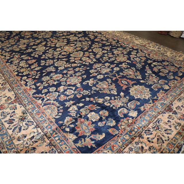 1910s Persian Sarouk rug woven with Manchester wool. An all-over sprayed floral design on a midnight blue field and...