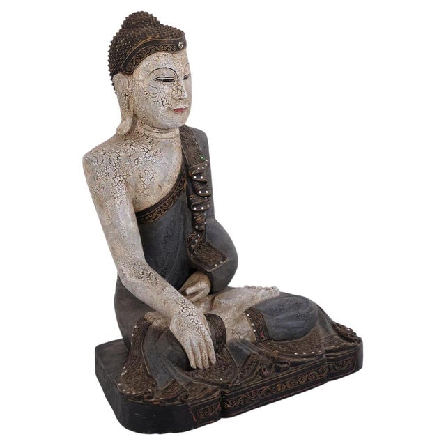 Decorative Buddha figure carved in wood with light tones and blue accents. Originating from Thailand and dating to the...