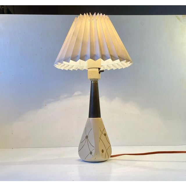 Italian 1950s table light composed of a lacquered wooden bas with handprinted atomic decor, a brass top and a white fluted...
