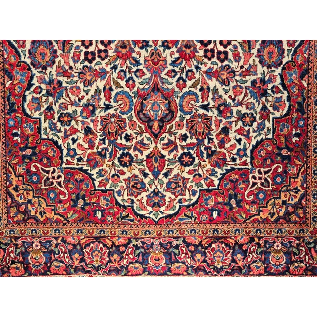 An early 20th century hand-knotted Persian Kashan rug, distinguished by its rare and coveted ivory field color and...