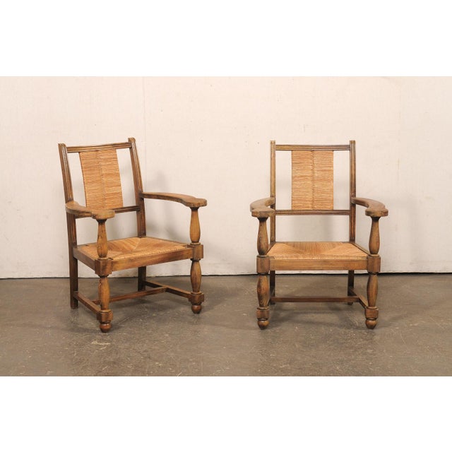 A handsome pair of Spanish wooden armchairs, with rush seat and backs, from the mid 20th century. This mid-century pair of...