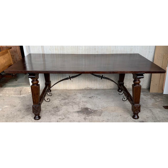 A Spanish Fratino dining table with hand made wrought-iron stretcher from the late 19th century. This Spanish wooden table...