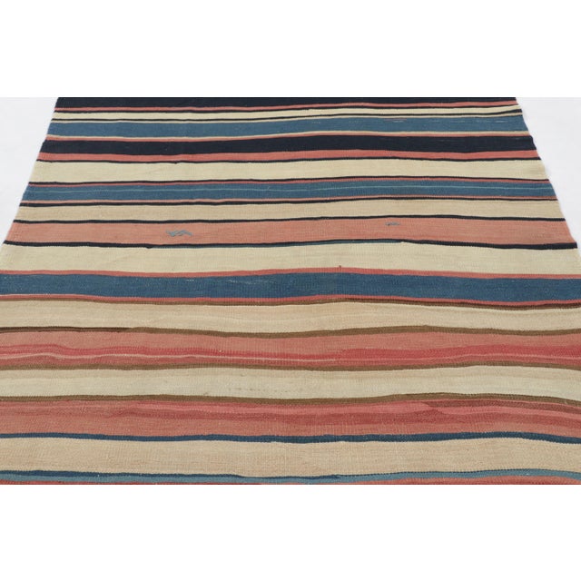 Made with handwoven wool circa 1950-1960, this 5x8 vintage Kilim is a particularly bright and sought-after work of an...