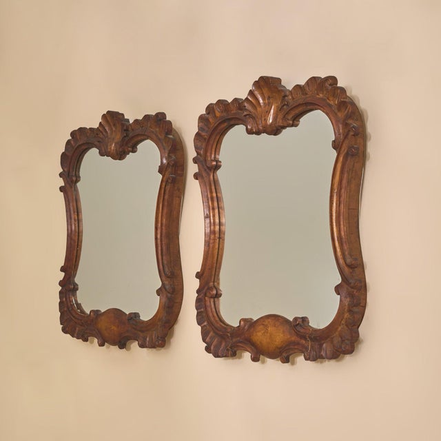 A petite 19th century French wall mirror, finely carved in wood and richly detailed with Rococo-inspired ornament. The...