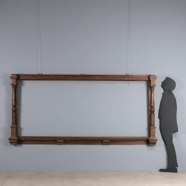 Large walnut mirror frame. The side uprights are turned and carved, as are the lower shelf brackets and the upper band....