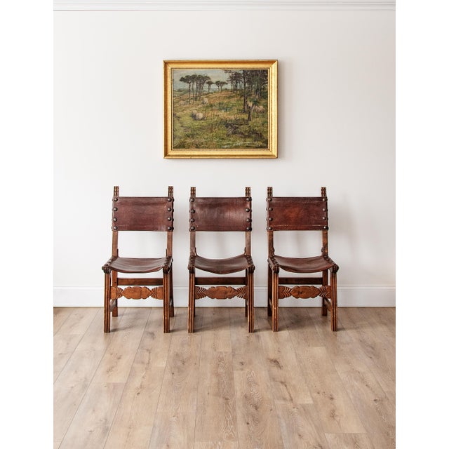 A handsome set of six vintage rustic Spanish dining chairs crafted from solid hardwood and fitted with rich saddle leather...