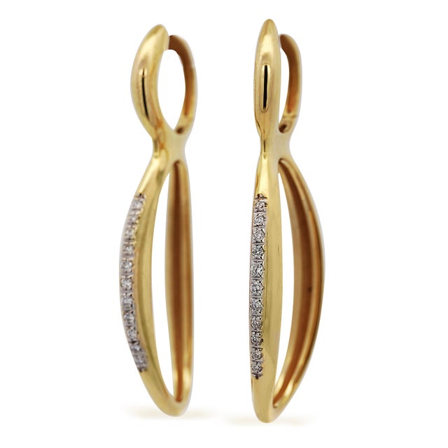 Italian-made 14K yellow gold long oval drop earrings feature 0.26 carats of round diamonds and a smooth high-polish oval...