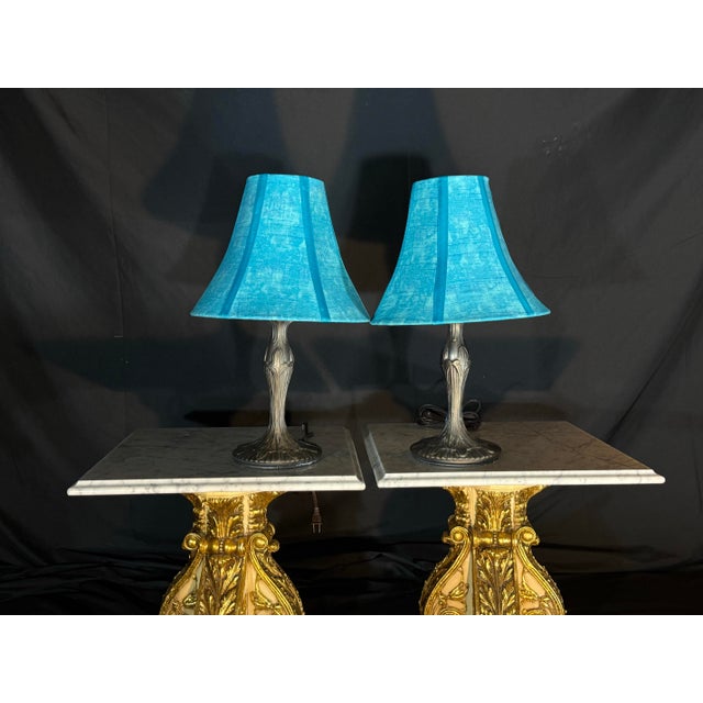 Matching pair of decorative table lamps featuring vibrant turquoise textured fabric shades and dark bronze-tone sculptural...