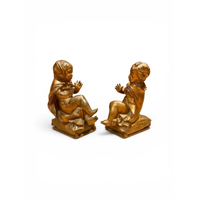 A pair of 19th century gilt bronze cherub putti bookends, each modeled as a seated child figure draped in fabric and...