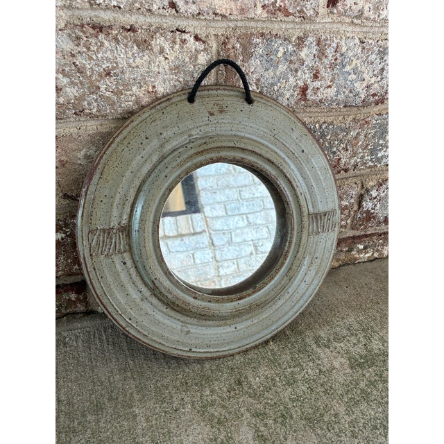 Vintage ceramic round wall mirror, featuring a unique speckled glaze over a pale green glazed base with textured side...
