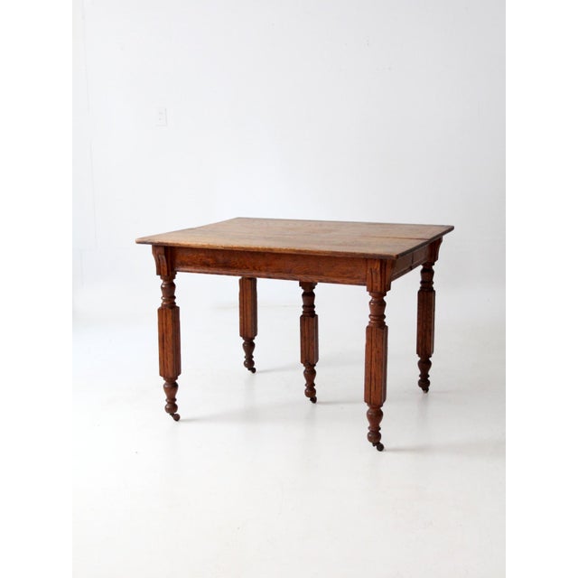 Antique wood dining table with beautifully carved balustrade legs, showcasing the craftsmanship and character of a classic...